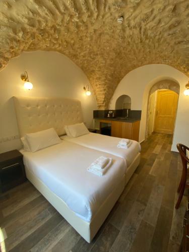 a bedroom with a large white bed with a stone ceiling at Petrakis Inn in Jerusalem