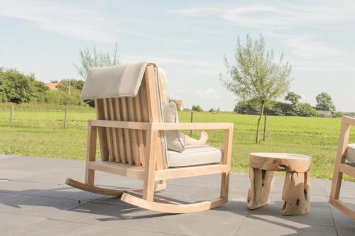 a wooden rocking chair with a person sitting in it at Slufterhoeve in De Cocksdorp