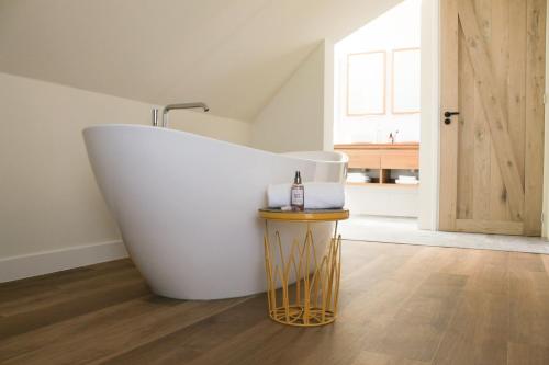 a large bath tub in a bathroom with a wooden floor at Slufterhoeve in De Cocksdorp