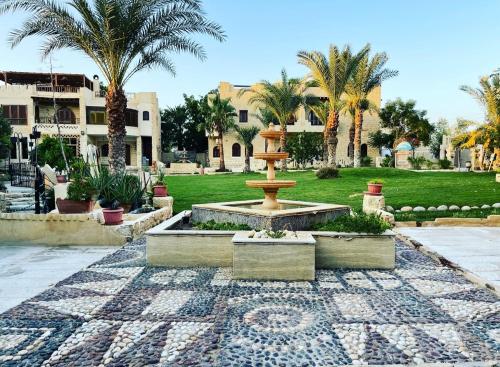 a fountain in the middle of a courtyard with palm trees at palm shadow resort in Tunis