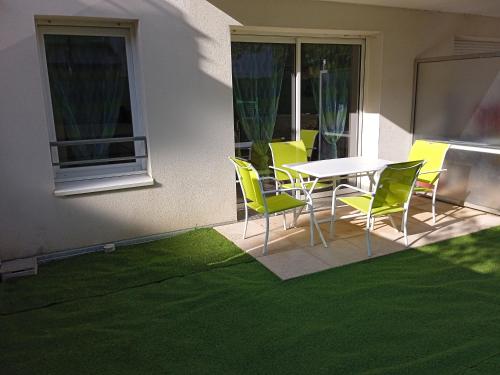einen Tisch und Stühle auf einer Terrasse mit grünem Gras in der Unterkunft Korelo in Ploemeur