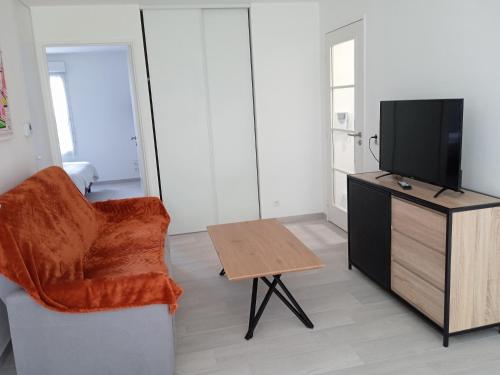 een woonkamer met een tv en een stoel en een tafel bij Korelo in Ploemeur