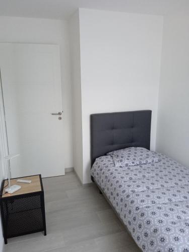 een kleine slaapkamer met een bed en een tafel bij Korelo in Ploemeur