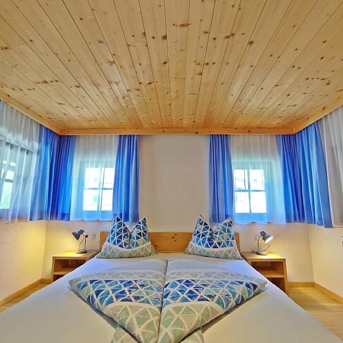 a bedroom with a large bed with blue curtains at Chalet Maurer in Cadipietra