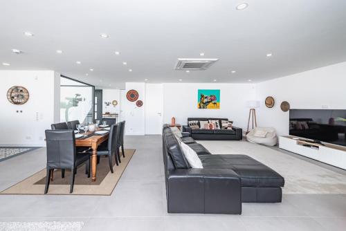 a living room with a table and black leather furniture at Casa da Oliveira ~ Azeitão in Azeitao