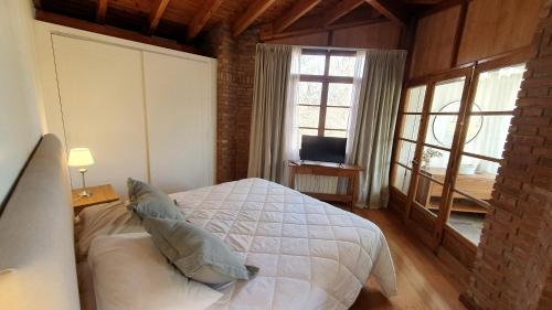 a bedroom with a white bed and a window at La Bignonia Posada in Chacras de Coria