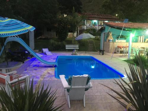 a swimming pool with a slide in a yard at night at Pousada Recanto dos Arcos in Conservatória