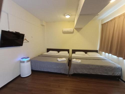 two beds in a room with a flat screen tv at SO Hotel in George Town