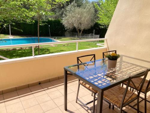 una mesa de cristal y sillas en un balcón con piscina en Acogedor chalet familiar en la Sierra Calderona, en Nàquera