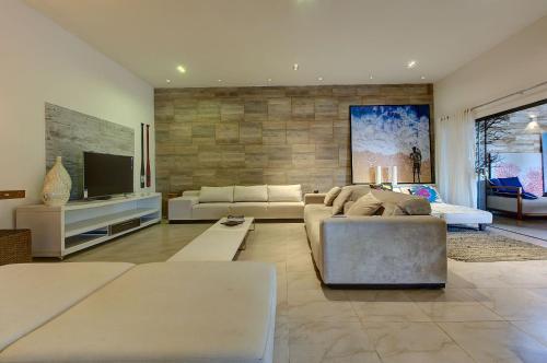 a living room with a couch and a tv at Casa Oásis com Sauna, Hidro e Piscina by Carpediem in Aquiraz