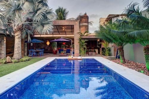 una piscina frente a una casa con palmeras en Casa Oásis com Sauna, Hidro e Piscina by Carpediem en Aquiraz