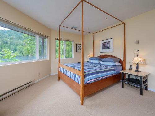 ein Schlafzimmer mit einem Himmelbett und einem Fenster in der Unterkunft North Lake Waterfront Home in Egmont
