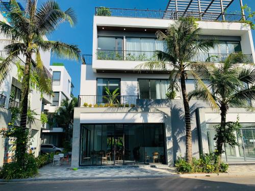 un bâtiment avec des palmiers en face de celui-ci dans l'établissement Joy Villa Flamingo Đại Lải - 5 phòng ngủ, à Phúc Yên