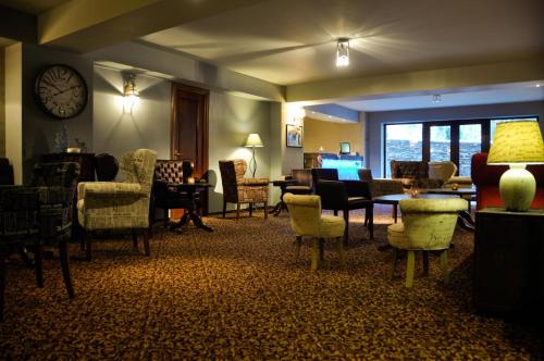 a waiting room with chairs and a table and a clock at Paj Hotelul Retreat & Spa in Sinaia