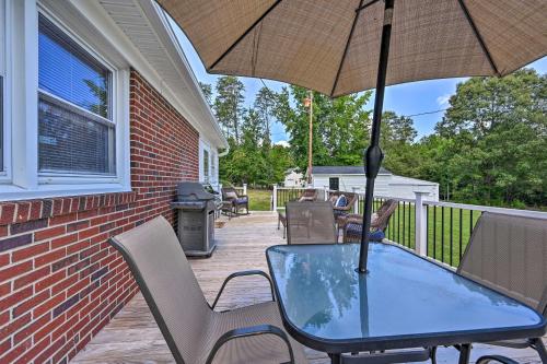 a table and chairs on a porch with an umbrella at Charming Retreat on 5 Acres with Deck and Grill! in Monticello