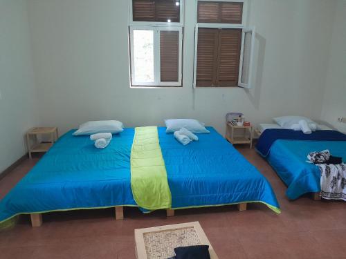 two beds in a room with blue sheets and towels at Pousada Rural Simpatia in Caculi