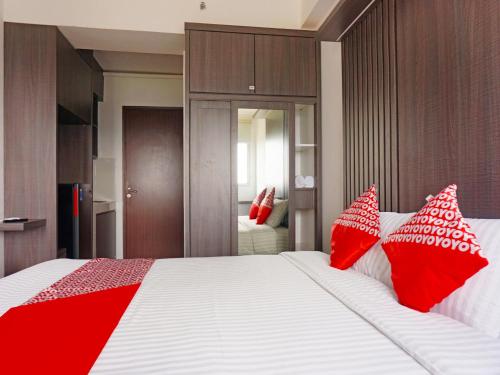 um quarto com uma cama grande com almofadas vermelhas em OYO 91593 San San Rooms Apartment Gunung Putri Square em Parungdengdek