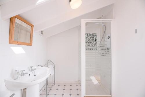 a white bathroom with a sink and a shower at The Shealing, Waldringfield (Air Manage Suffolk) in Waldringfield