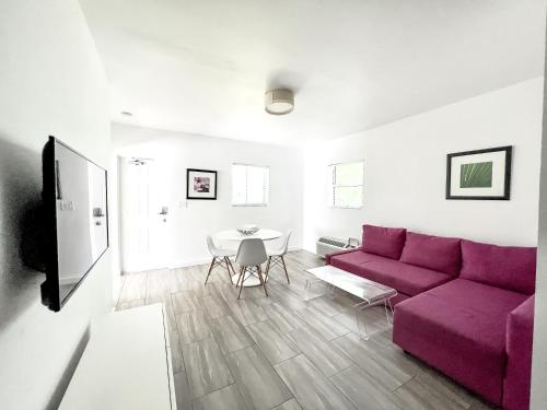 Una sala de estar con un sofá morado y una mesa. en Beach Gardens, en Fort Lauderdale