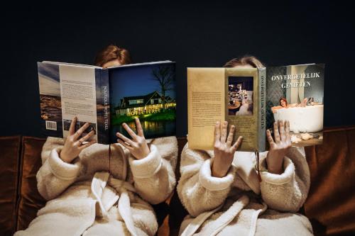 a group of people laying in bed reading books at Slufterhoeve in De Cocksdorp