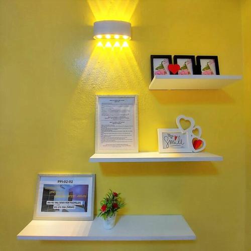 a yellow wall with shelves with pictures and a light at Comfy Stay @Permai Puteri Ampang nearby KLCC, IJN in Ampang