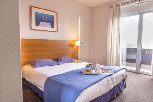 a hotel room with a bed with a tray of food on it at Hôtel Savoie Léman in Thonon-les-Bains