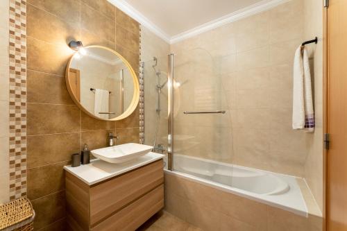 a bathroom with a sink and a tub and a mirror at Casa Boa Onda in Nazaré