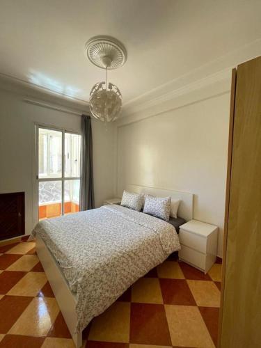een slaapkamer met een bed en een kroonluchter bij Ifrane Appartment in Ifrane