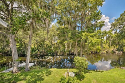 a pond in a park with trees and a house at Old Florida Setting with Kayaks and Fishing Poles in Inverness