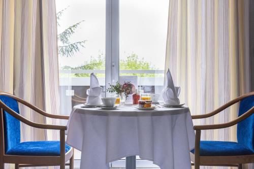 einen Tisch mit 2 Stühlen und einen Tisch mit einem weißen Tischtuch in der Unterkunft Hôtel Savoie Léman in Thonon-les-Bains