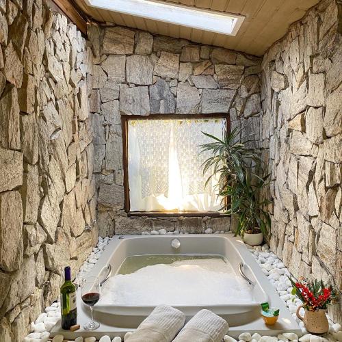 维奥康德马奥Chalés Canto Do Rio的带浴缸的石质浴室设有窗户。