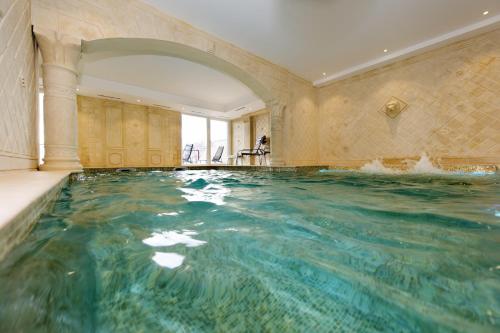 an indoor pool in a building with water in it at Alexain Hotel Restaurant & Wellness - Colmar Ouest in Trois-Épis