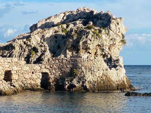 a large rock in the water with acknowled at Blue Marine Taormina in Taormina