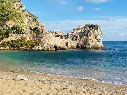 a sandy beach next to the ocean with a rocky cliff at Blue Marine Taormina in Taormina
