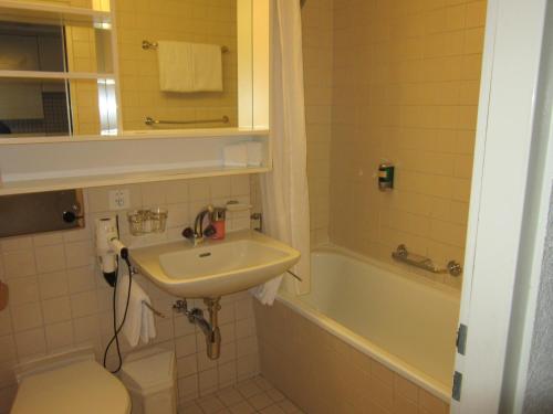 a bathroom with a sink and a toilet and a tub at Studio im Hotel Des Alpes in Flims