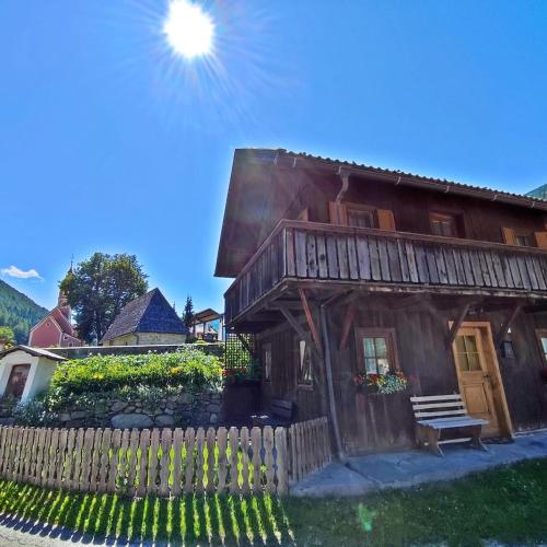 a wooden house with a bench next to a fence at Chalet Maurer in Cadipietra