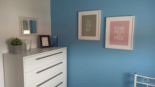 a blue room with a dresser and two pictures on the wall at Sea Breeze luxury apartments in Nea Vrasna