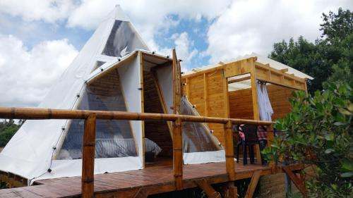 a cabin with a pyramid roof on a wooden deck at Alas Glamping La Cima in Guatavita