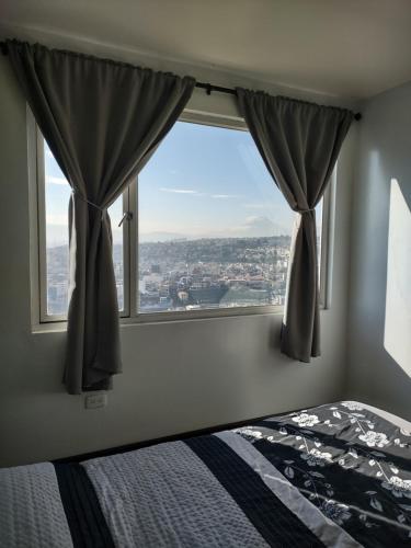 um quarto com uma cama e uma grande janela em Hermosa Casa Vacacional en Ambato sector Pinllo CON UNA VISTA ÚNICA DE LA CIUDAD em Ambato