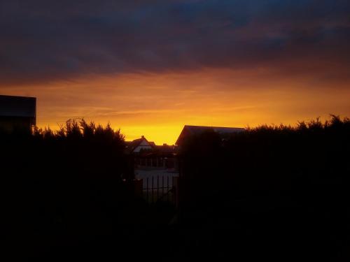 a sunset with a building and a fence in the foreground at Baltazar in Łeba