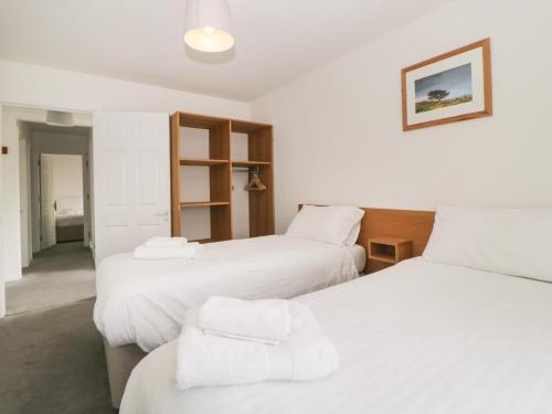 a room with three beds with white sheets at Harcombe House Bungalow 3 in Newton Abbot
