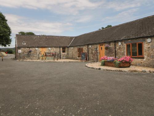 a stone building with flowers in front of it at Harcombe House Bungalow 3 in Newton Abbot