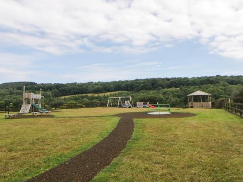 an empty park with two swings and a playground at Harcombe House Bungalow 3 in Newton Abbot
