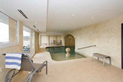 a pool in a room with chairs and a table at Alexain Hotel Restaurant & Wellness - Colmar Ouest in Trois-Épis
