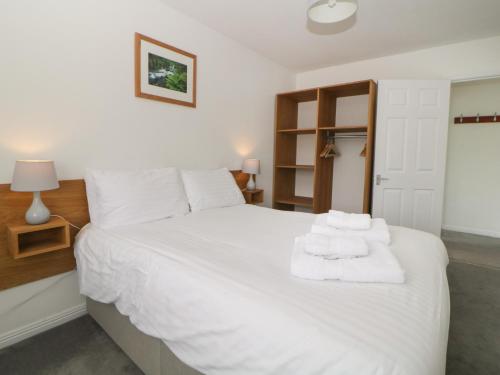a bedroom with a white bed with towels on it at Harcombe House Bungalow 10 in Newton Abbot