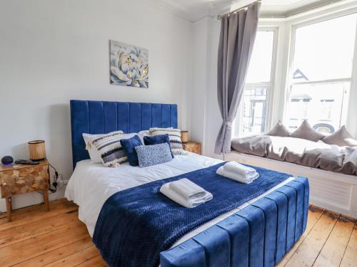 a bedroom with a blue bed with towels on it at The Bookcase in Colwyn Bay