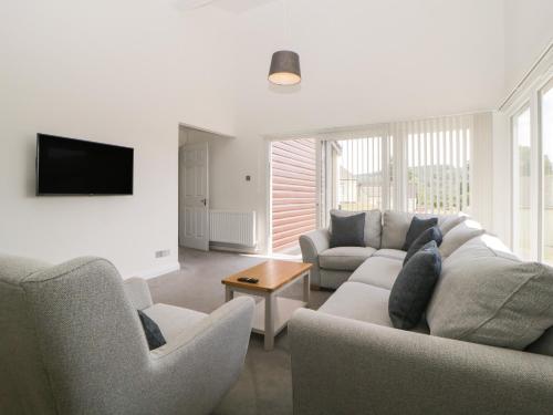 a living room with a couch and two chairs and a tv at Harcombe House Bungalow 2 in Newton Abbot