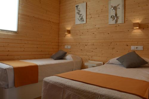 two beds in a room with wooden walls at Cabañas Compostela - Cabaña a Carballeira in Santiago de Compostela