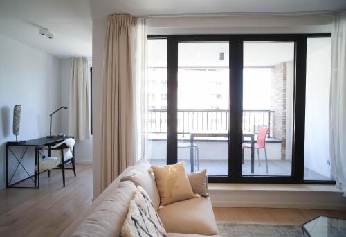 een woonkamer met een bank en een groot raam bij The Erasmus Flats in Brussel