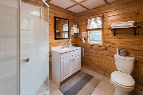 La salle de bains est pourvue de toilettes, d'un lavabo et d'une douche. dans l'établissement Madawaska Lodge-Cottage, à Madawaska